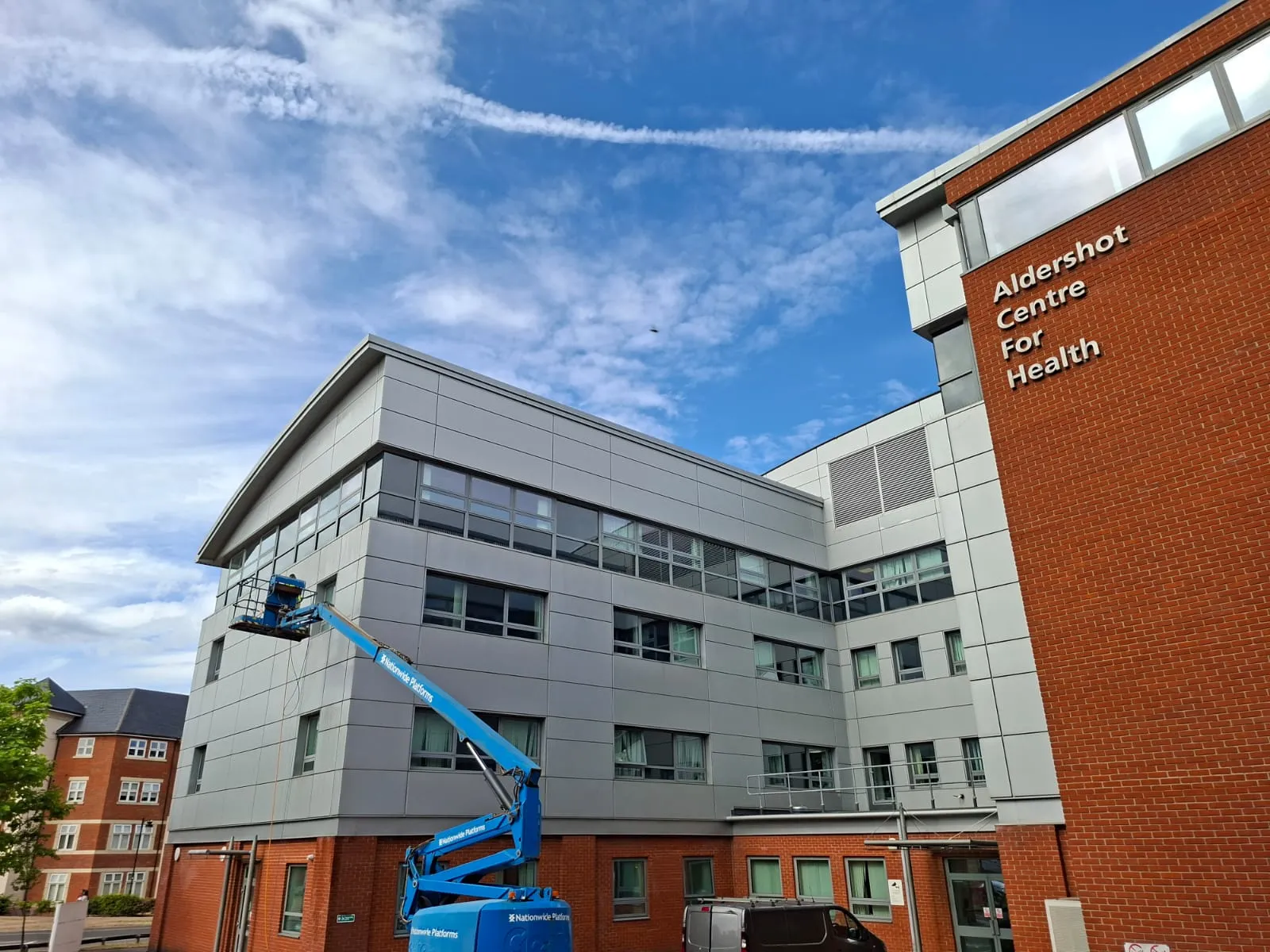 A man is working on a crane in front of a building.