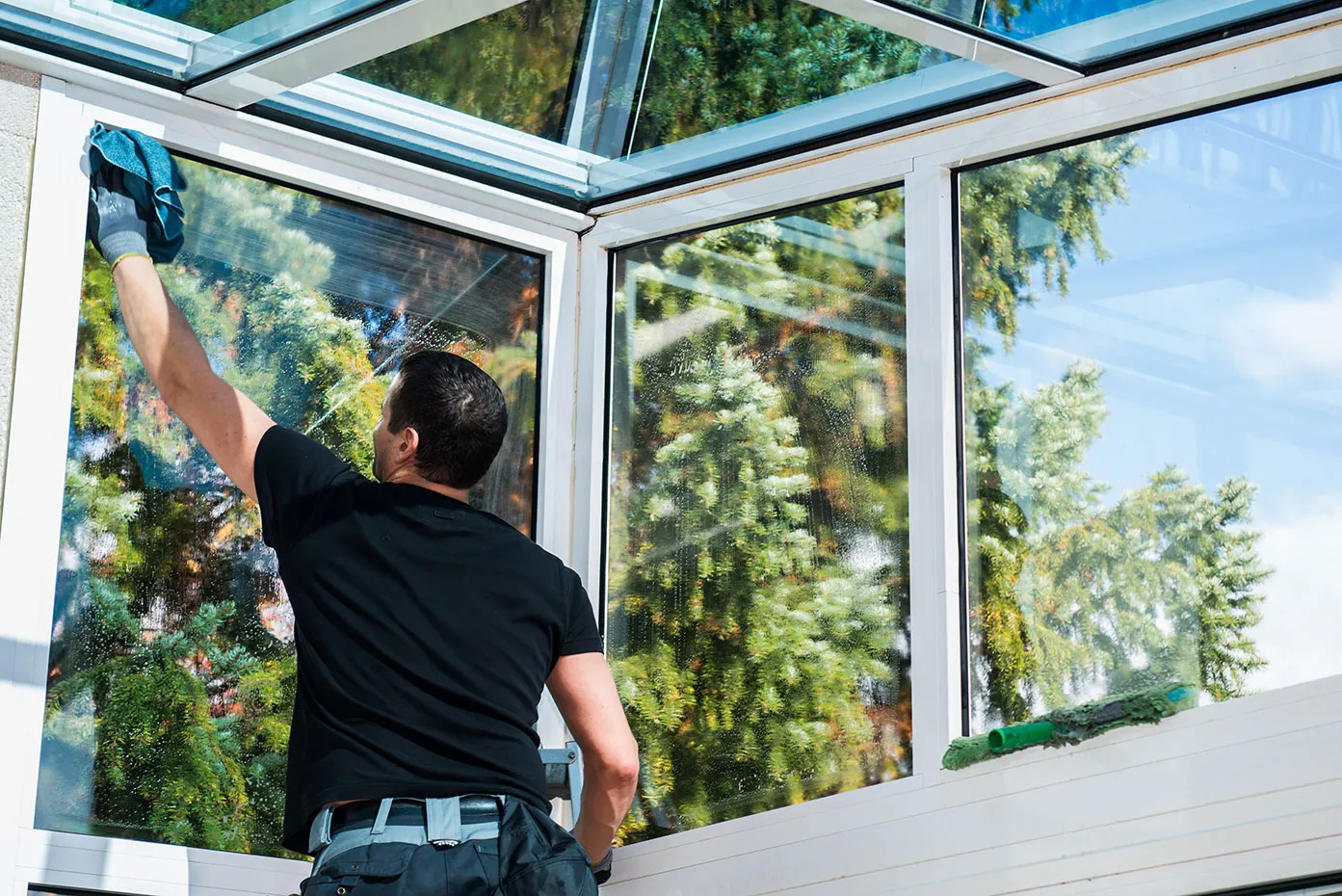 A man painting a window with a roller.